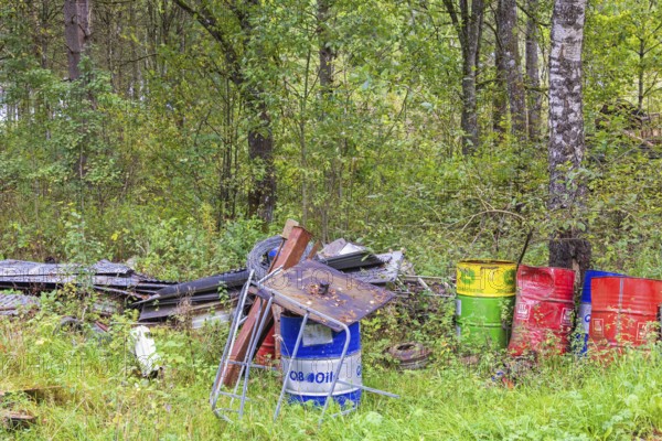 Environmental destruction with abandoned oil barrels and scrap metal in the forest