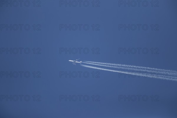 Boeing 747 aircraft of Lufthansa airlines flying across a blue sky leaving a contrail or vapor