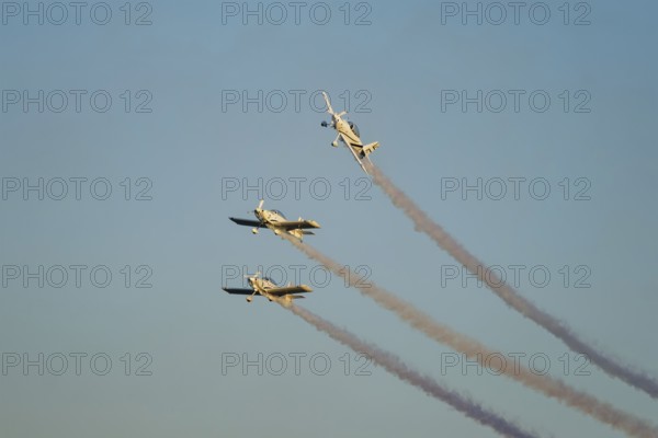 Three stunt aerobatic planes performing stunts in blue sky with smoke trail. Concept of teamwork,