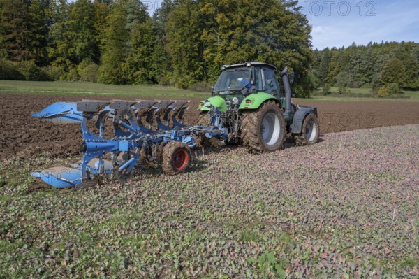 Farmer with tractor ploughing his field with a 5-turn rotary plough, Franconia, Bavaria, Germany,