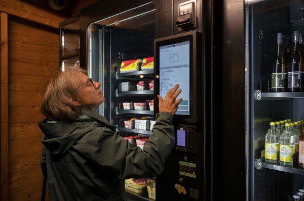 Elderly woman buying groceries at vending machine, display, food vending machine, farm shop,