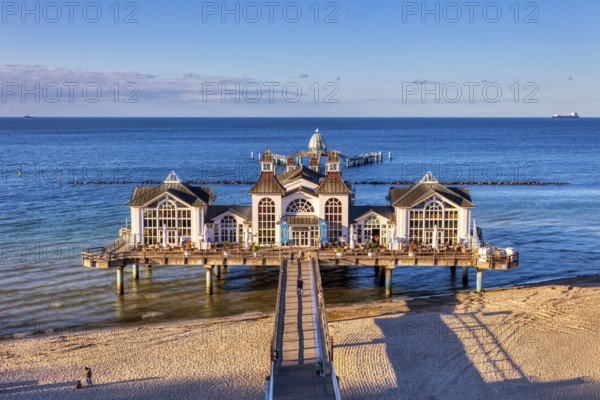 Symmetrical view of the pier with historic building above the blue sea and sand, Rügen, Sellin