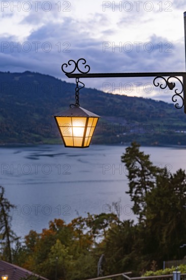 A glowing lantern with a view of a lake in a mountainous landscape, St. Beatus Caves, Switzerland,