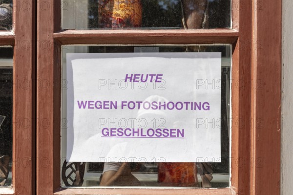 Closed shop with sign due to photo shoot in wooden frame window, Vienna