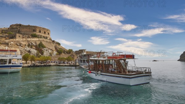 A white boat lies in a quiet harbour near a historic fortress under a blue sky, Venetian Sea
