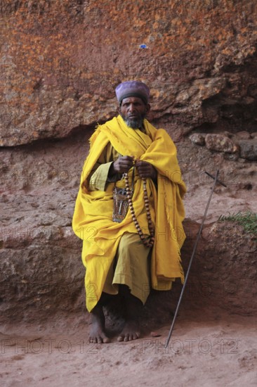 Rock churches of Lalibela, pilgrim prays with a rosary in front of a rock church, Ethiopia, Africa