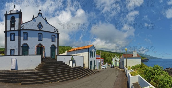 White church Igreja de São João Baptista on the village square in coastal location with clear sky