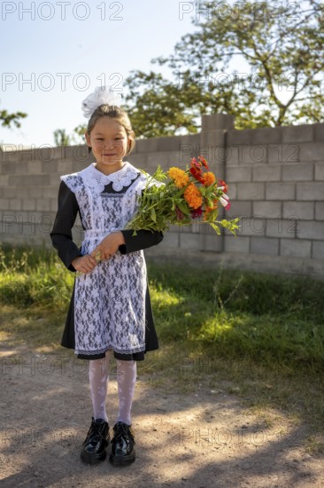 Schoolgirl with a bouquet of flowers on her first day at school, Issyk-Kul region, Kyrgyzstan, Asia