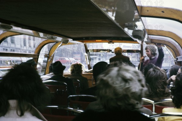 People sitting inside boat trip tour through the city centre Amsterdam, Netherlands 1973 Tour guide