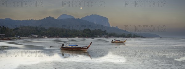 Before sunrise, longtail boats lie at low tide in the harbour at Sivalai Beach, Koh Mook Island,