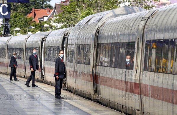 Deutsche Bahn train attendants wear face masks shortly in front of the departure of an ICE train at
