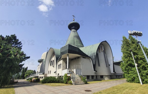 White modern church with green roof and cross against blue sky, Cathedral of the Holy Trinity,