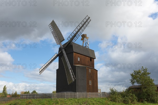 Historic wooden windmill under a cloudy sky in a landscape, Paltrock windmill, Parey, Elbe-Parey,