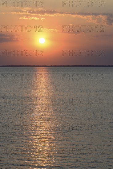 Sunset over the calm North Sea, the outline of the island of Juist on the horizon, Norddeich, Lower