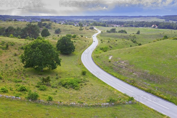 Aerial view of winding road curves through the hills of Brösarps backar, Brösarp's slopes in