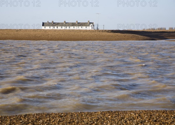 White terrace of Coastguard Cottages, beach and sea viewed from offshore, Shingle Street, Suffolk,