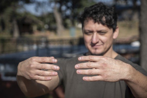 A middle-aged Caucasian man assumes the static posture of Tree Hugging, an essential technique in