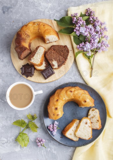Cakes with raisins and chocolate and a cup of coffee. lilac flowers on a gray concrete background,