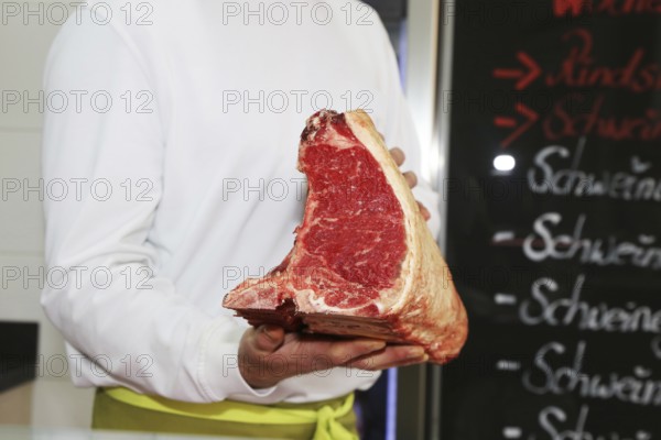 Butcher holds a dry aged T-bone steak in his hand