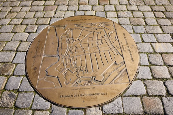 Fountain of the Materni Hospital, bronze fountain slab, cobblestone pavement, street An der