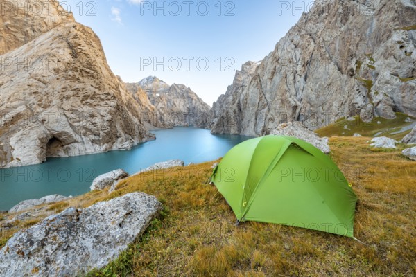 Green tent at the turquoise mountain lake Kol Suu with rocky steep mountains, Kol Suu Lake, Sary