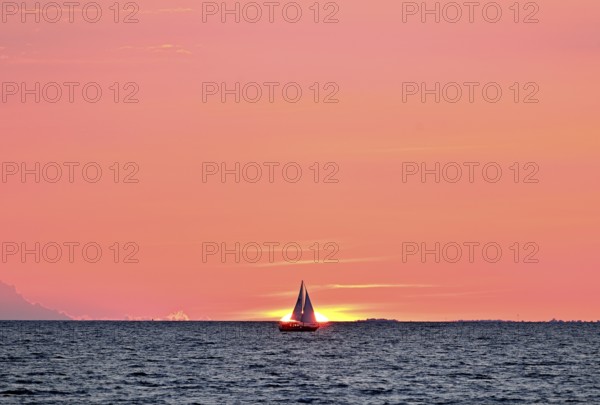 Sailboat sailing in the evening towards the setting sun, Baltic Sea, Poel Island,