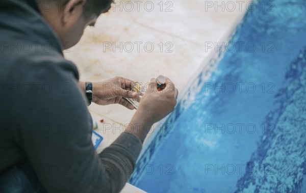 Tester kit to measure chlorine and ph in swimming pools. Person testing the PH of the pool