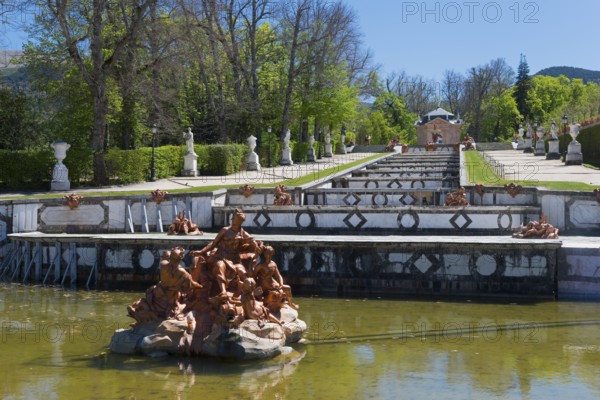 Baroque fountain with detailed sculptures in a park setting with green trees, Royal Castle La