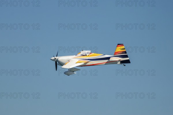 Stunt aerobatic plane performing stunts in blue sky. Concept of speed, difficulty, precision, risk,