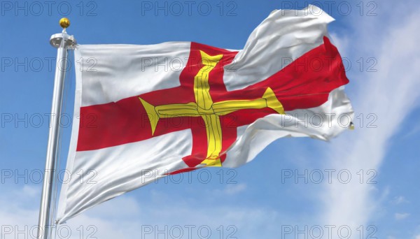 The flag of the Isle of Guernsey, Great Britain, flutters in the wind