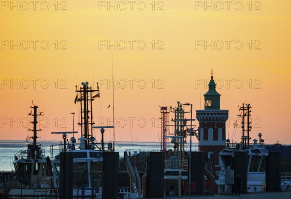 Harbour at sunset with various boats and the sea in the background, the sky in bright orange,