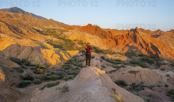 Hiker between red rocks, canyon of eroded sandstone formations, red and orange sandstone rocks,