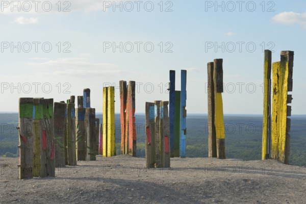 A creative art installation of colourfully painted wooden posts with abstract patterns against a