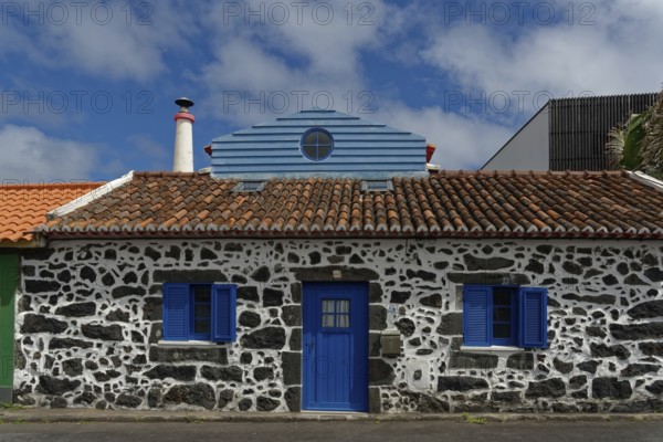 Former whaler's stone house with blue shutters and door, traditional tiled roof, narrow chimney,
