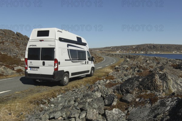 Camper/caravan on a lonely coastal road through the tundra to Hamningberg (in the background) on