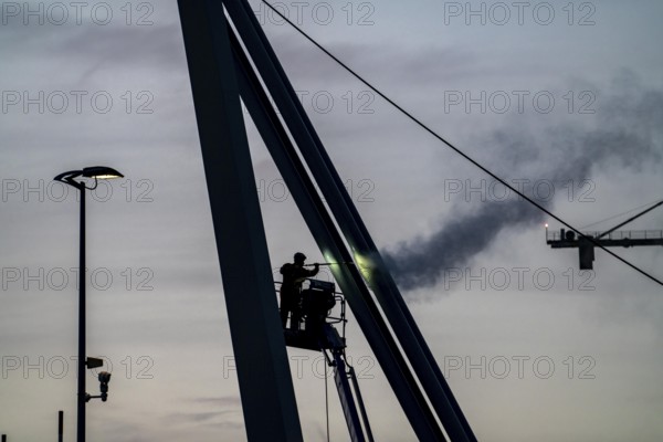 Worker cleans a bridge pier with a high-pressure cleaner on a cherry picker at the Erasmus Bridge