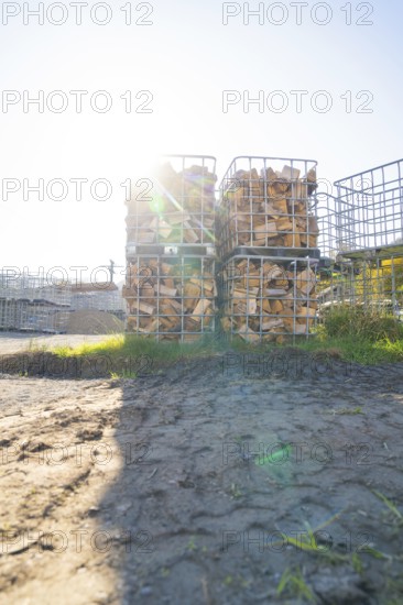 Stacked pieces of wood in metal frames in a meadow with sunshine and shade, refugee accommodation