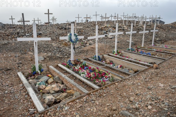 Crosses decorated with colourful flowers mark graves in a rocky area, cemetery, remote Arctic Inuit