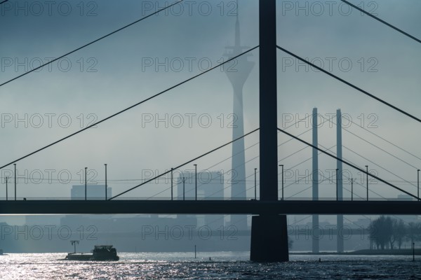 Dense fog slowly lifting, cargo ships on the Rhine near Düsseldorf, in front the Oberkassler
