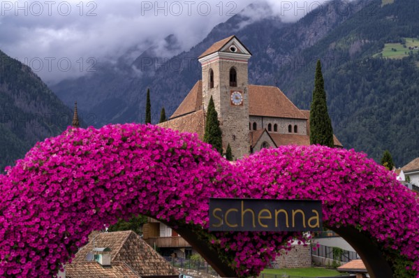 Photopoint, sign, flower heart, heart made of flowers, behind it the new parish church Maria