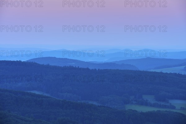 Undulating hills and mountains in blue and pink evening twilight, creating a calm and peaceful