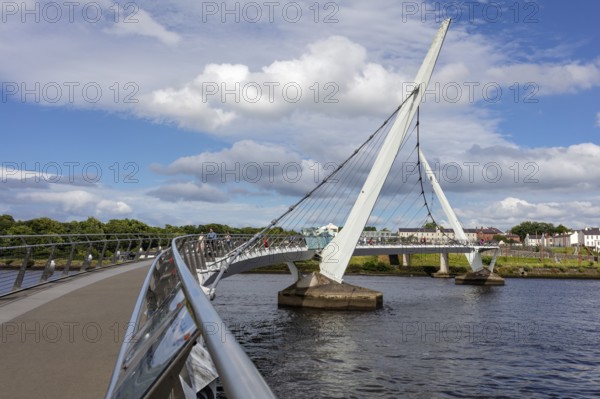 An impressive bridge arch stretching over a river under a cloudy sky, Londonderry
