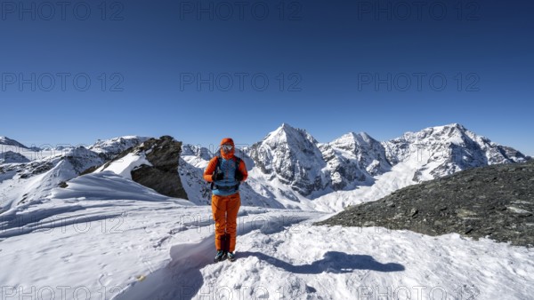 Ski tourer on foot at the summit of the Madritschspitze, mountain panorama with snow-covered