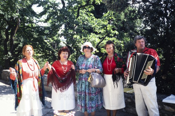 Accordion folk music group in front of Yalta, Crimea, Russia, 1997 Woman posing with the musicians,
