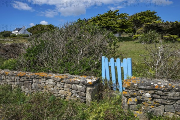 Pors Poulhan, Brittany, France - Picturesque dry stone wall with blue garden gate on the GR36