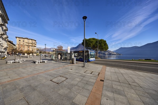 Bus stop, public bus, hilly landscape, blue sky with veil clouds, Lake Lugano, street Riva Vincenzo