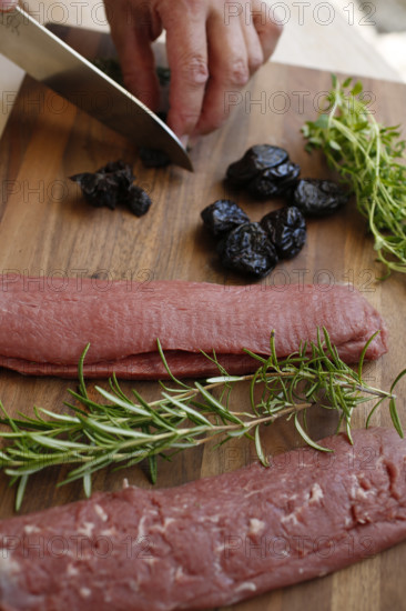 Swabian cuisine, preparation of lamb with prunes, raw lamb, rosemary, herbs, sliced garlic, lemon