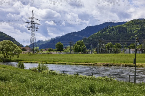River Kinzig, bank with meadow and trees, electricity pylon, transformer station, hilly landscape