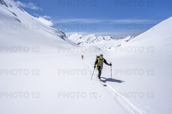 Two ski tourers in a mountain landscape with snow, behind summit Mittaghorn and Wildhorn, ascent to