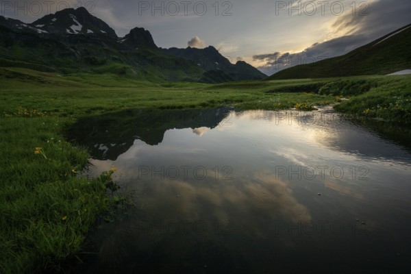 Summit in the morning light with dramatic clouds and stream in the foreground, Lech,